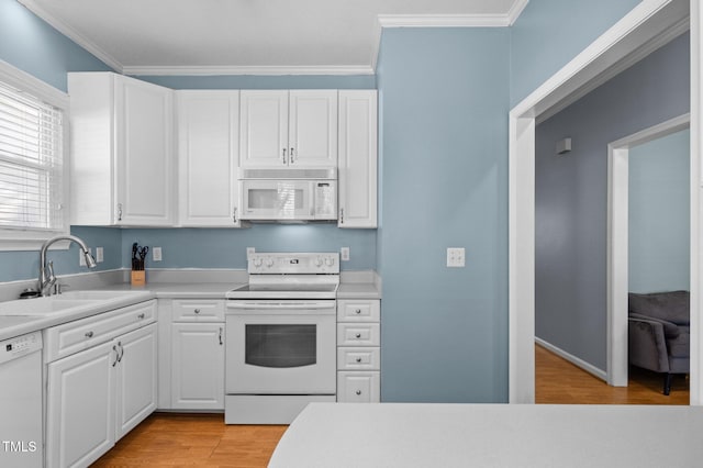 kitchen with light wood-style flooring, white appliances, ornamental molding, and a sink