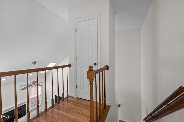 stairs featuring wood finished floors and a ceiling fan