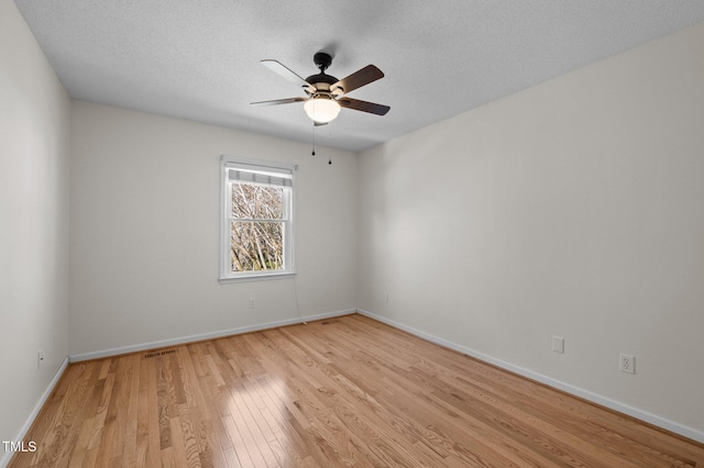 spare room with baseboards, visible vents, light wood finished floors, and ceiling fan