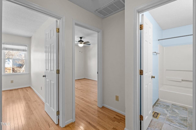 hallway featuring baseboards, visible vents, and light wood-type flooring