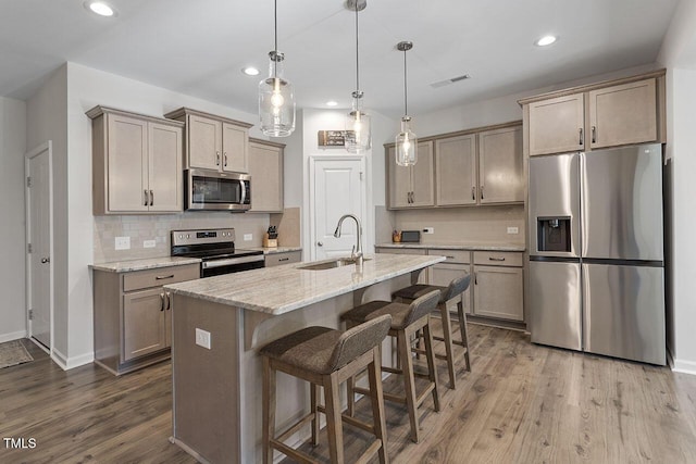 kitchen with visible vents, a sink, dark wood-type flooring, appliances with stainless steel finishes, and a kitchen breakfast bar