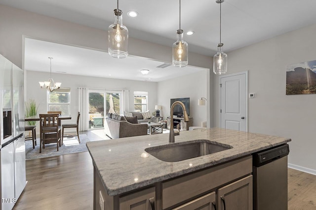 kitchen featuring fridge with ice dispenser, a sink, light stone counters, stainless steel dishwasher, and wood finished floors