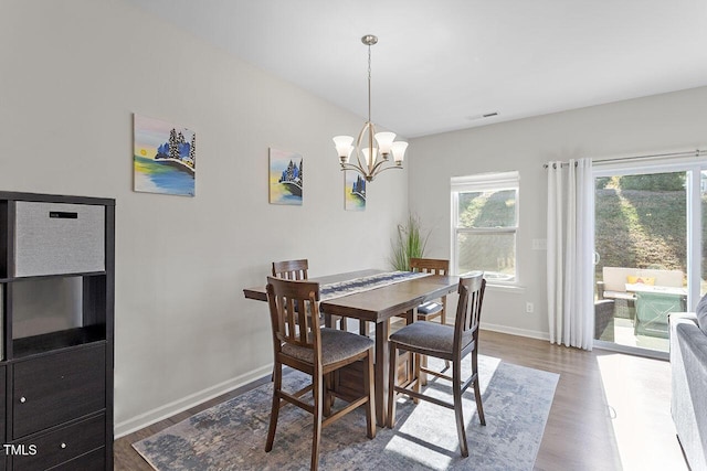 dining area featuring a notable chandelier, visible vents, baseboards, and wood finished floors