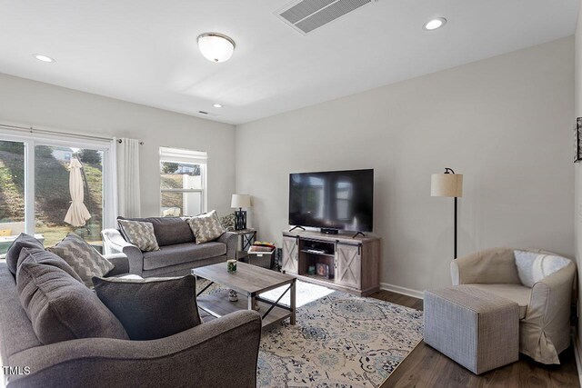 living room with recessed lighting, visible vents, baseboards, and wood finished floors