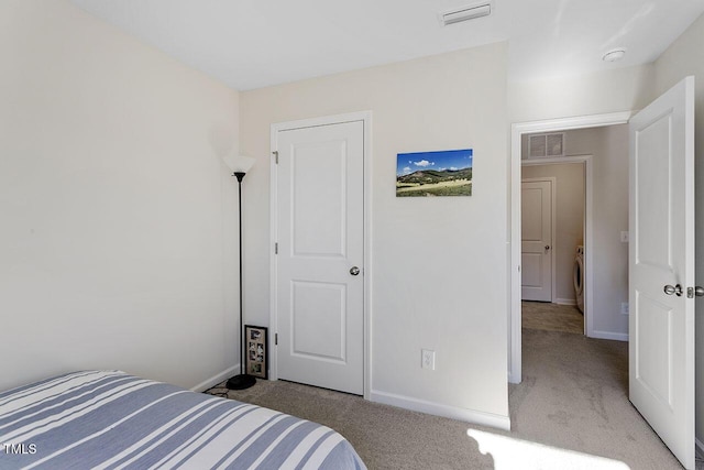 carpeted bedroom with visible vents, baseboards, and washer / dryer