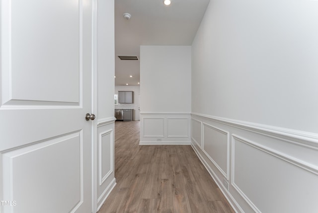 hall featuring visible vents, a decorative wall, wood finished floors, and recessed lighting