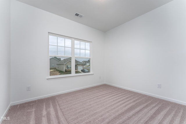 empty room with carpet, visible vents, and baseboards