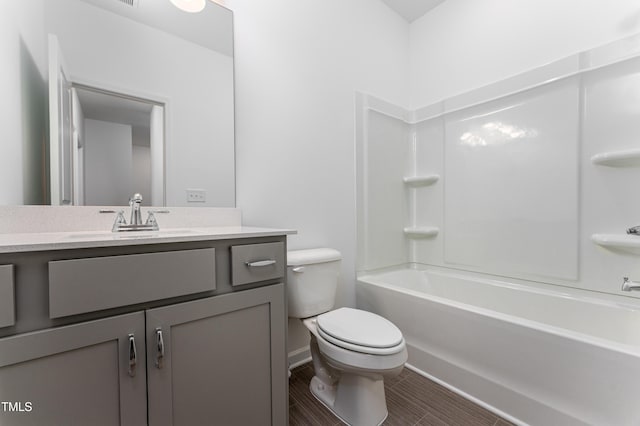 bathroom featuring toilet, baseboards, shower / washtub combination, and vanity