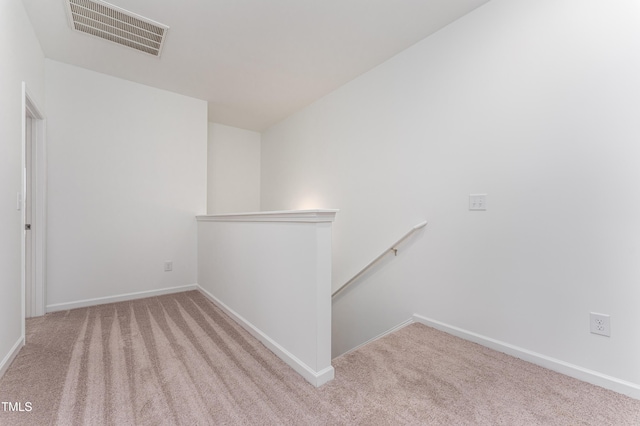 empty room with carpet floors, visible vents, and baseboards