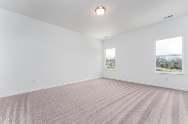 empty room with light carpet, visible vents, and baseboards