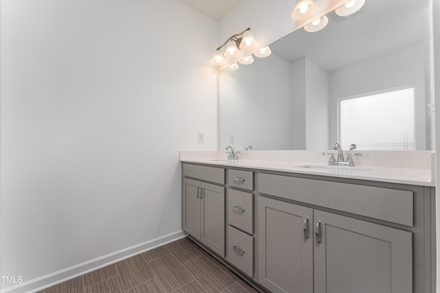 full bathroom featuring double vanity, baseboards, and a sink