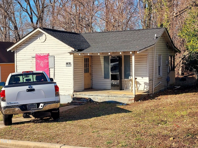 view of front of house with a front yard and a shingled roof