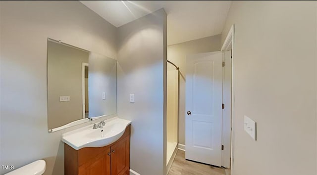 bathroom with toilet, wood finished floors, a shower stall, and vanity