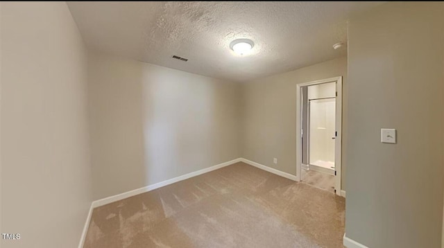 spare room featuring a textured ceiling, carpet flooring, visible vents, and baseboards