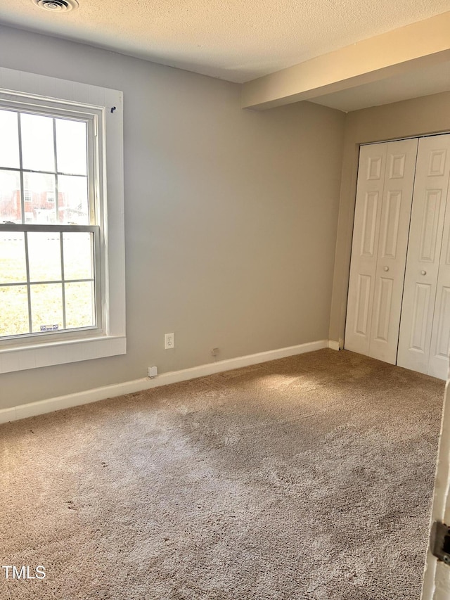 unfurnished bedroom with carpet, baseboards, and a textured ceiling