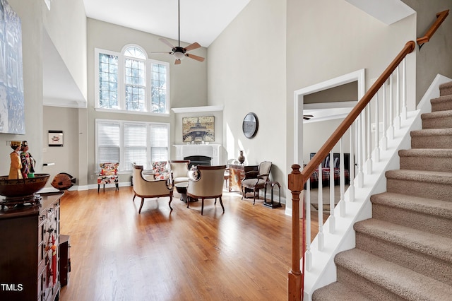 living area with stairs, plenty of natural light, wood finished floors, and ceiling fan