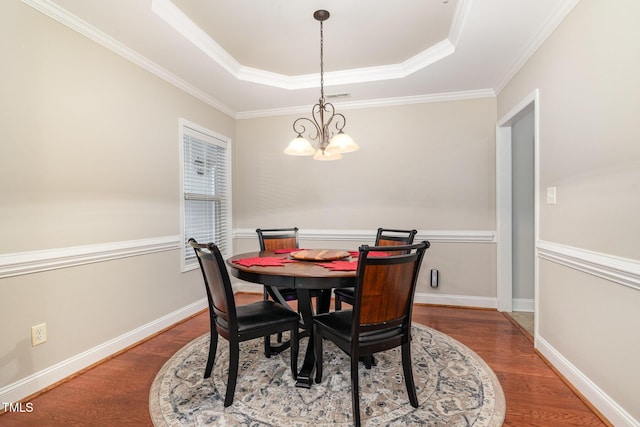 dining area featuring a tray ceiling, baseboards, an inviting chandelier, and wood finished floors