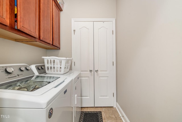 washroom featuring washing machine and clothes dryer, cabinet space, and baseboards