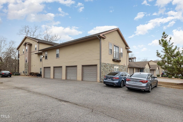 view of property exterior with aphalt driveway and stone siding