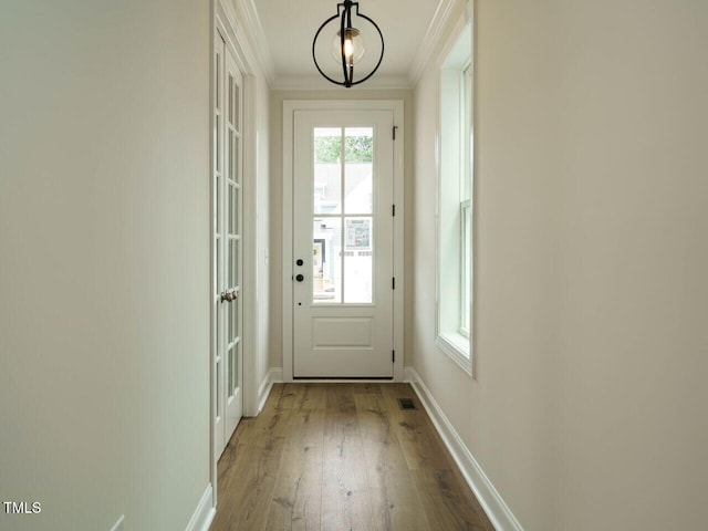 entryway with baseboards, visible vents, hardwood / wood-style flooring, and crown molding