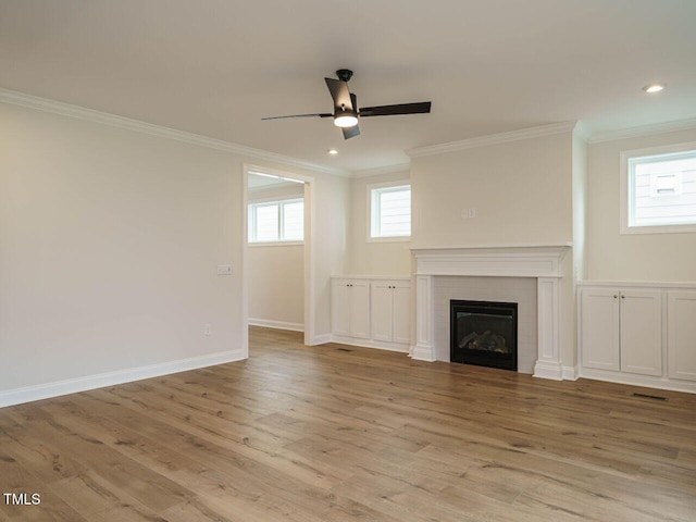 unfurnished living room featuring a brick fireplace, baseboards, crown molding, and wood finished floors