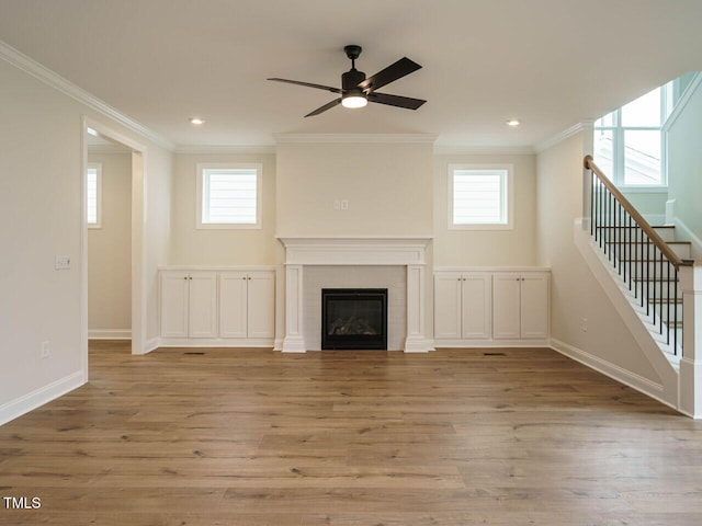 unfurnished living room with ornamental molding, stairway, wood finished floors, and a tile fireplace