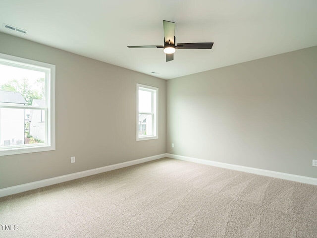 spare room featuring light carpet, baseboards, visible vents, and ceiling fan