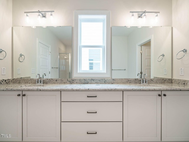 bathroom featuring double vanity, a shower stall, and a sink