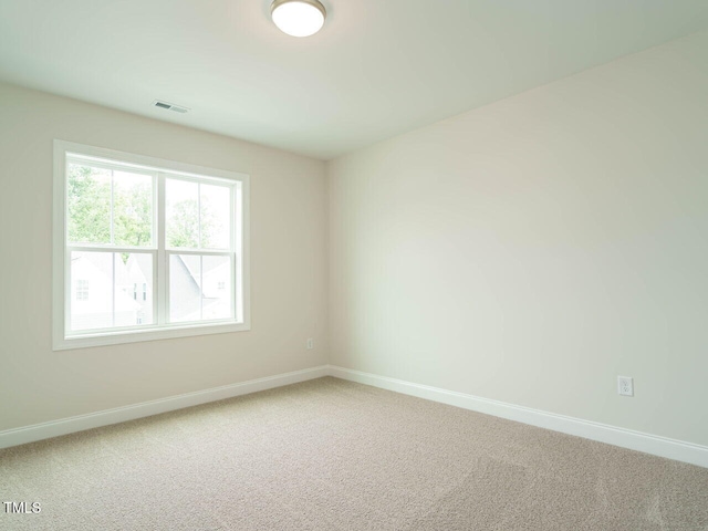 empty room with carpet flooring, visible vents, and baseboards