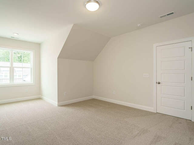 additional living space featuring carpet, visible vents, lofted ceiling, and baseboards