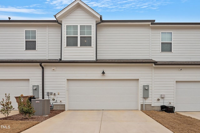 exterior space featuring an attached garage, central AC unit, and driveway