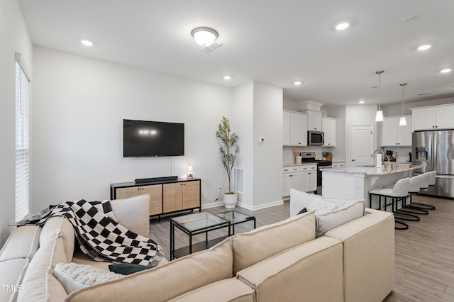 living room featuring recessed lighting, visible vents, baseboards, and light wood-style floors