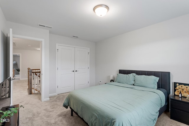 bedroom featuring baseboards, visible vents, light carpet, and a closet