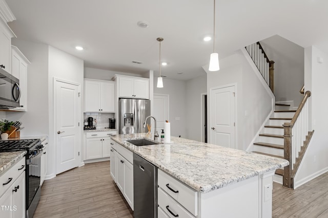 kitchen featuring a sink, white cabinetry, light wood finished floors, and stainless steel appliances