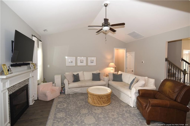 living room featuring visible vents, a glass covered fireplace, ceiling fan, dark wood-style flooring, and vaulted ceiling