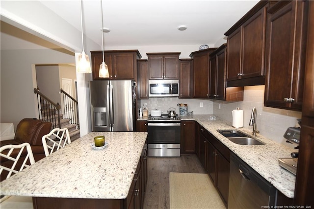 kitchen featuring dark wood-type flooring, a kitchen island, a sink, appliances with stainless steel finishes, and backsplash