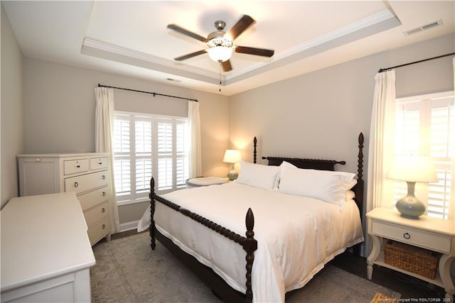 bedroom featuring a ceiling fan, a tray ceiling, visible vents, and crown molding