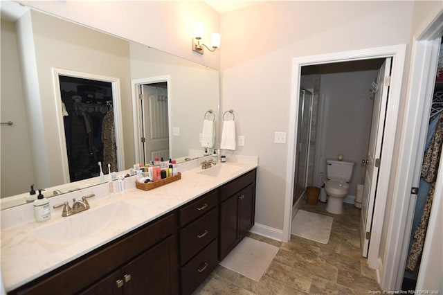 bathroom featuring a walk in closet, a sink, toilet, and double vanity