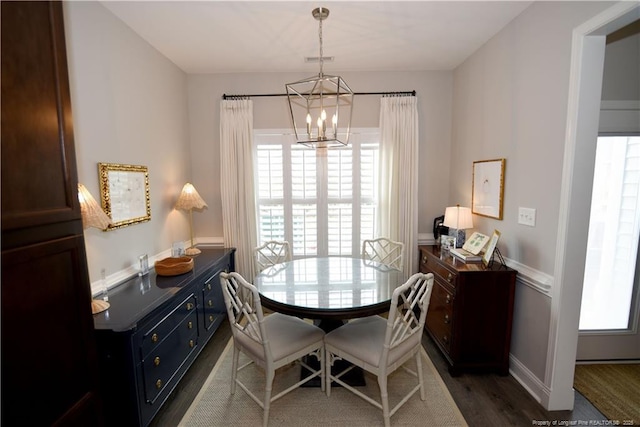 dining space featuring baseboards, dark wood-style flooring, and an inviting chandelier