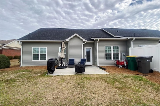 back of house with a patio, a yard, a shingled roof, and fence