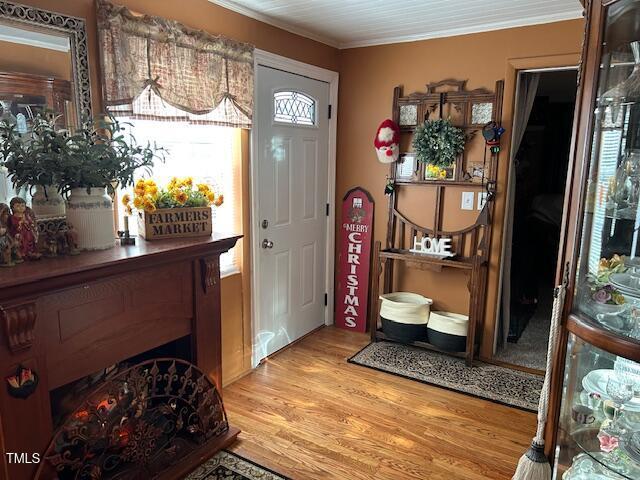 foyer entrance with light wood finished floors and ornamental molding