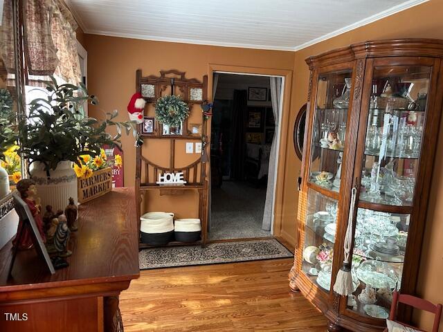 hallway with crown molding and wood finished floors