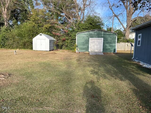 view of yard with a storage shed, an outdoor structure, and fence