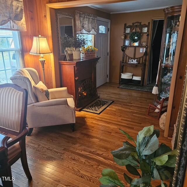 living area with wood finished floors, a fireplace, and ornamental molding