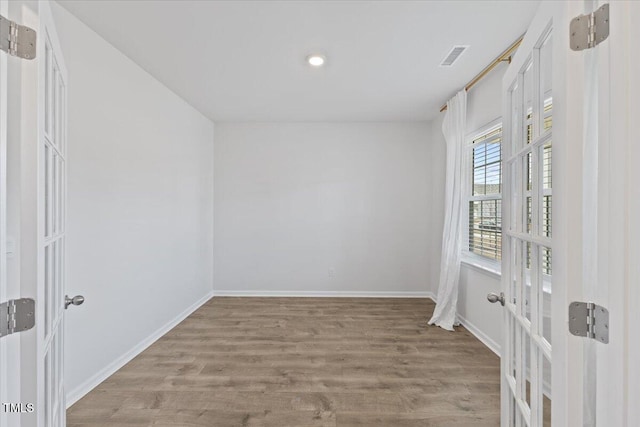 empty room with visible vents, light wood-style flooring, and baseboards