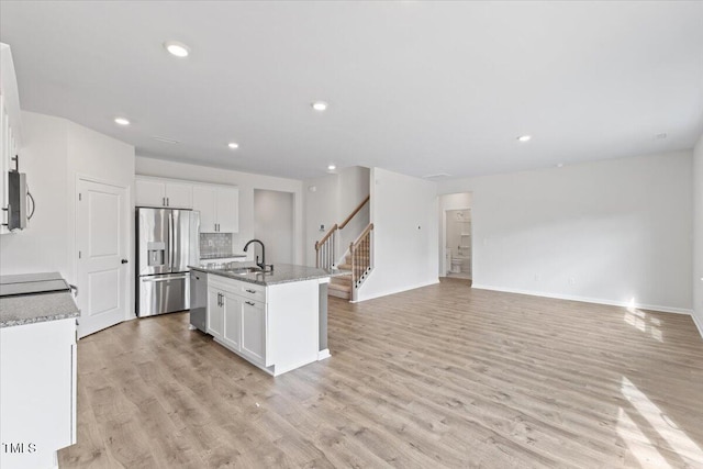 kitchen featuring appliances with stainless steel finishes, white cabinetry, a sink, and light wood-style flooring