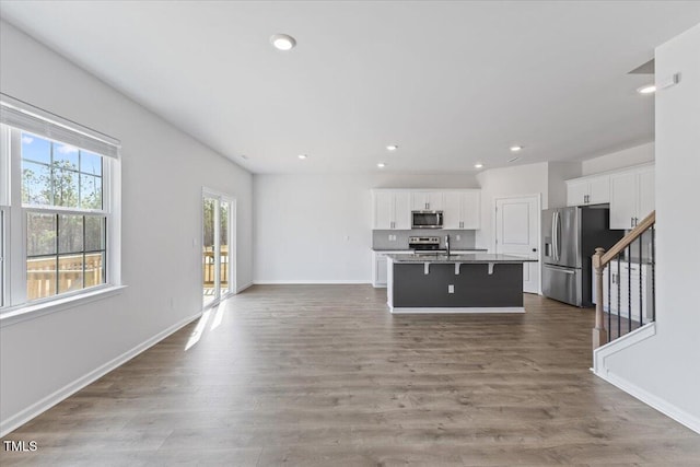 kitchen with appliances with stainless steel finishes, open floor plan, white cabinetry, and dark wood-style floors