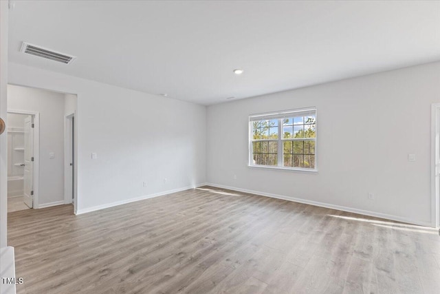 unfurnished room featuring wood finished floors, visible vents, and baseboards