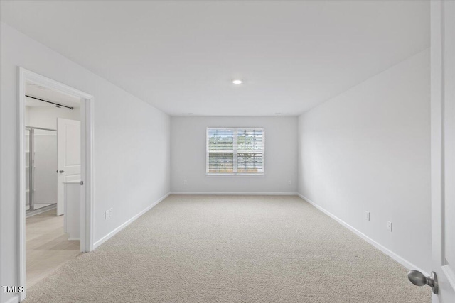 spare room featuring baseboards and light colored carpet