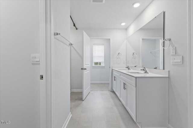 full bathroom featuring double vanity, baseboards, a sink, and recessed lighting